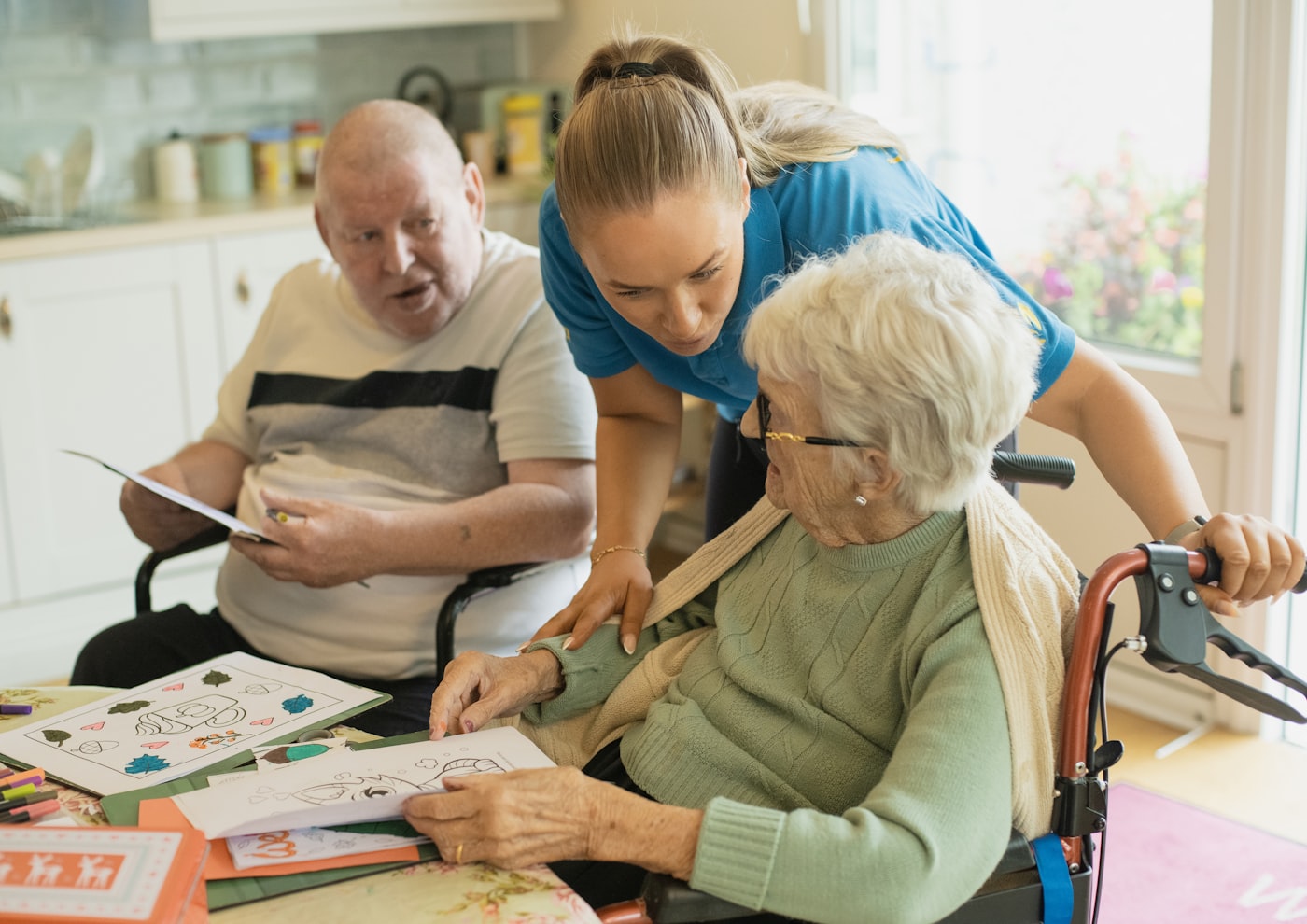 Caregiver supporting older adults with a tabletop activity - the kind of functional, everyday-living work occupational therapy websites should reflect